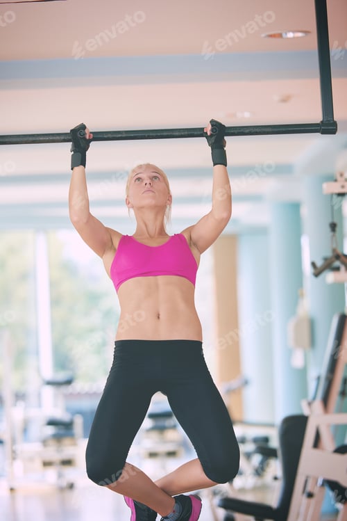Preview: young woman in fitness gym lifting on bar