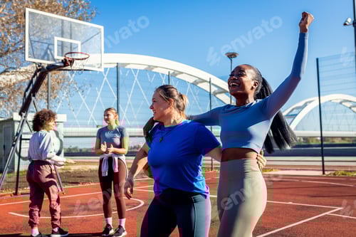 Preview: Diverse group of young woman having fun playing recreational basketball outdoors.