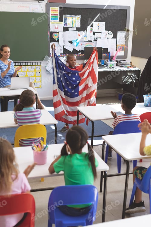 Preview: Schoolboy holding american flag in classroom at school