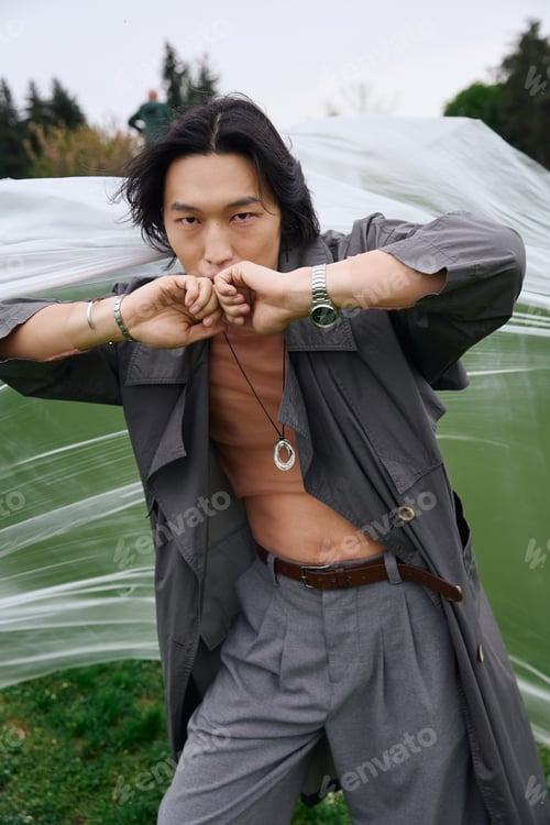 Preview: Stylish young asian man showcasing fashion in a scenic park setting