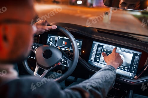 Preview: Using navigation display. Handsome unshaved man in fashionable clothes riding his automobile