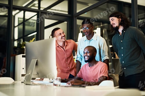 Preview: Shot of a group of designers looking at something on a computer while working late