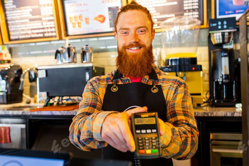Preview: Professional barista young redhaired ginger bearded man in black apron working in coffee shop