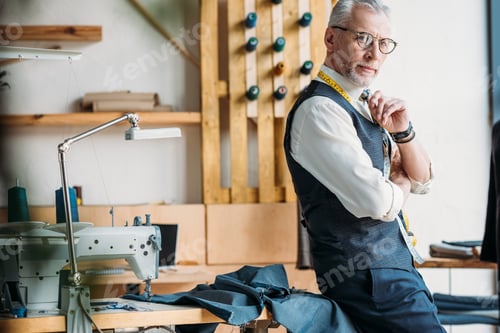 Preview: handsome pensive tailor standing at sewing workshop