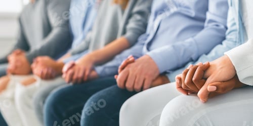 Preview: Unrecognizable people sitting in row and holding hands during therapy session