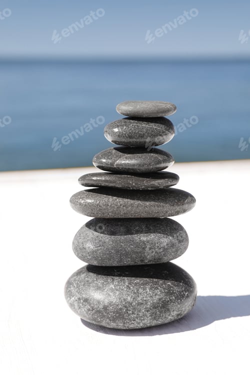 Preview: Stack of stones on wooden pier near sea. Zen concept