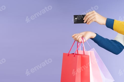 Preview: hand carrying shopping bags and showing a credit card