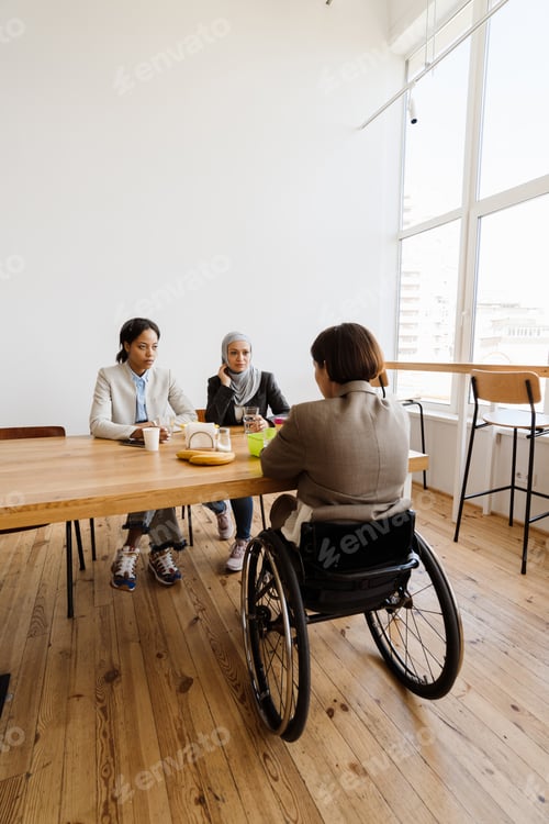 Preview: Three multiracial women discussing project while having break in office