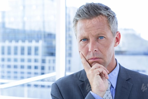 Preview: Senior businessman in formal suit standing by glass panels in office tower overlooking city skyline