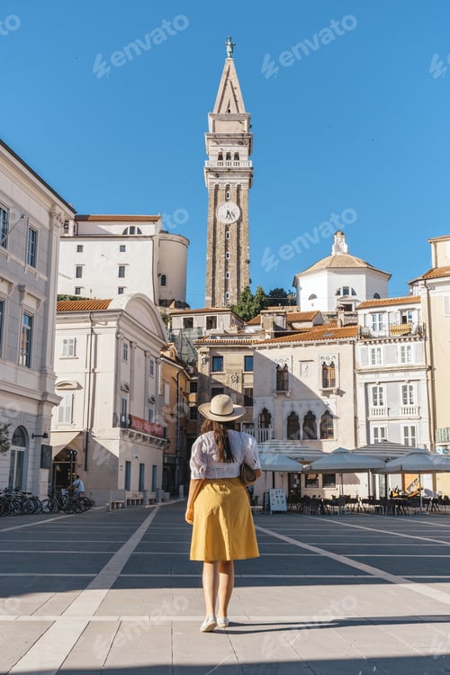 Preview: Rear view of a young woman standing on Tartini square in Piran, Slovenia