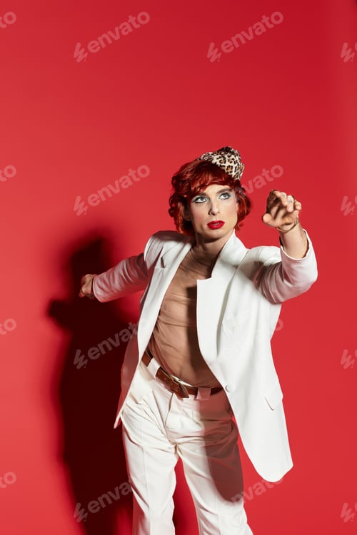 Preview: A young man flaunts a playful style against a bold red backdrop, brimming with confidence.