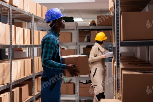 Preview: Factory shipping department employee standing with cardboard box