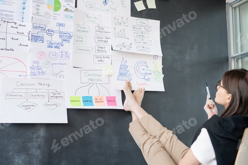 Preview: Young barefoot businesswoman sitting in front of blackboard and analyzing data