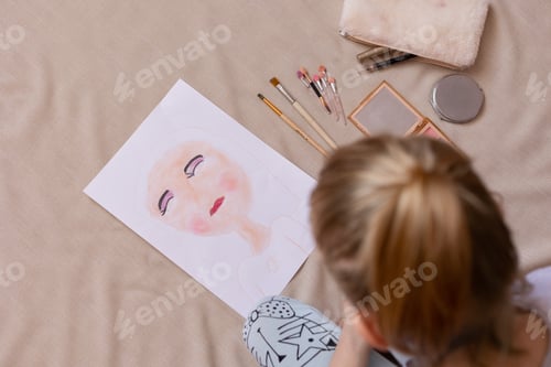 Preview: A small child girl draws a portrait with her mother's cosmetics.