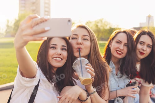 Preview: Group of young happy carefree girls friends making selfie on summer city street, sunset time