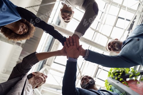 Preview: Happy group of multi ethnic coworkers stacked hands together as concept of corporate unity
