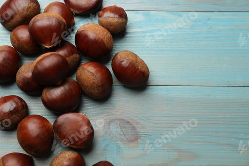 Preview: Roasted edible sweet chestnuts on light blue wooden table, flat lay. Space for text