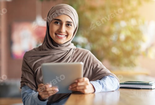 Preview: Happy girl in hijab with digital tablet smiling at camera