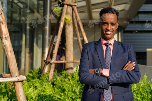 Preview: Portrait of successful young African businessman wearing suit and tie with arms crossed