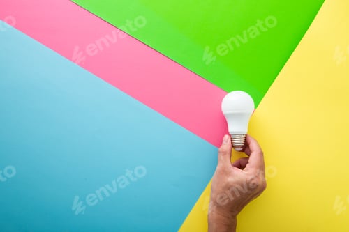 Preview: Hand with white light bulb on color background in pastel colors. Bright idea concept,