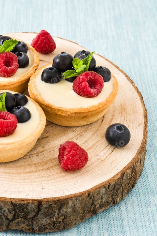 Preview: Delicious mini tarts with fresh raspberries and blueberries on wooden board