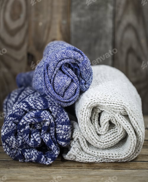 Preview: Rolled Knitted Throws on Rustic Wooden Surface