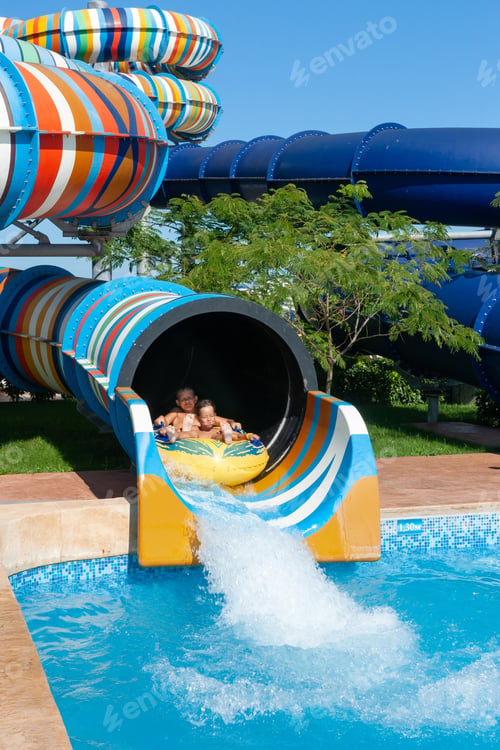 Preview: children on a rubber boat in the water park ride down the water slide