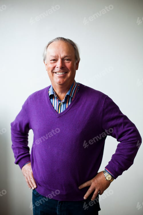 Preview: Portrait of happy senior man standing with hands on hip against white wall
