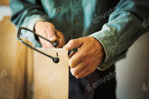 Preview: A man using a handsaw on a piece of wood.