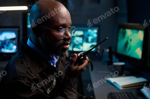 Preview: Black Man Communicating Security Alert Using Two Way Radio Indoors