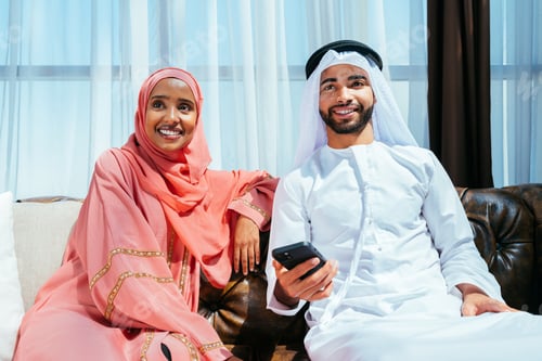 Preview: Happy middle eastern couple wearing traditional arab clothing at home