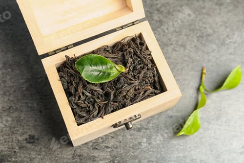 Preview: Wooden box with dry tea and green leaves on table