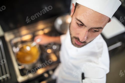 Preview: Chef stirring pan on stove, elevated view