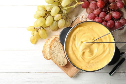 Preview: Flat lay composition with pot of delicious cheese fondue on wooden table