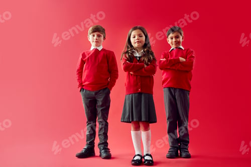 Preview: Group Of Elementary School Pupils Wearing Uniform Folding Arms Against Red Studio Background