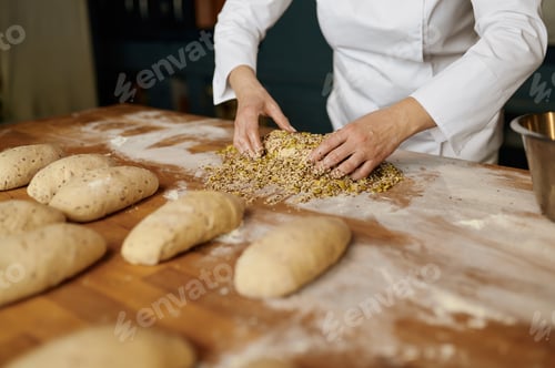 Preview: Portrait of positive female baker shaping bread bagels with seeds