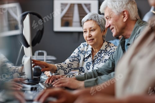 Preview: Senior man and woman looking at computer screen in class for senior people