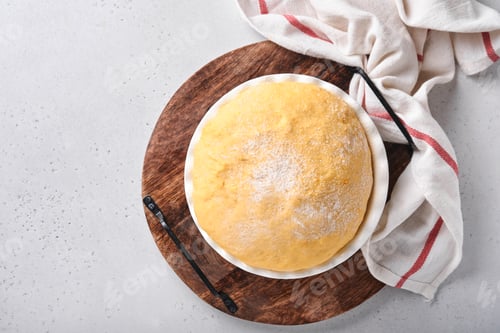 Preview: Raw yeast dough with pumpkin in white bowl covered with towel on the floured kitchen table, recipe i