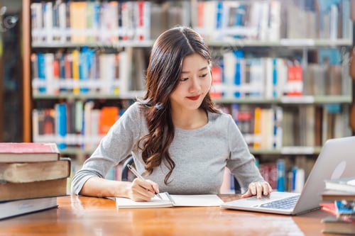 Preview: Asian young Student in casual suit doing homework and using technology laptop in library