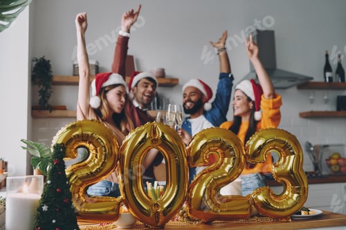 Visualização: Jovens felizes celebrando o Ano Novo com decoração dourada em primeiro plano