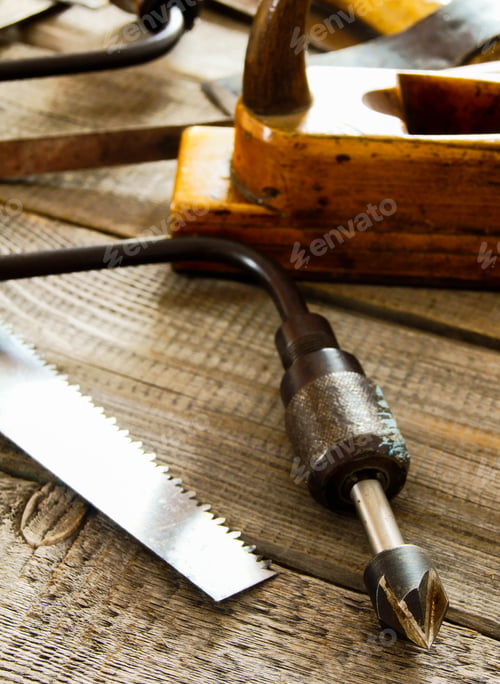 Preview: Many old working tools ( saw, plane and others) on a wooden background.