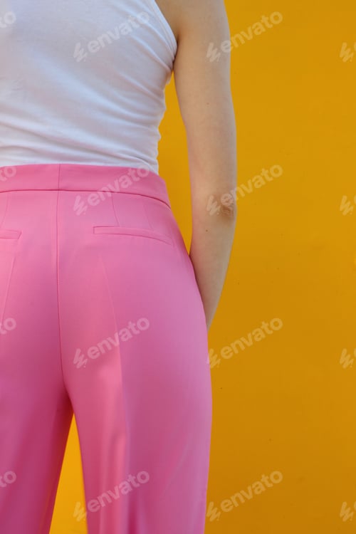 Woman Wearing Pink Trousers Posing Against Yellow Wall