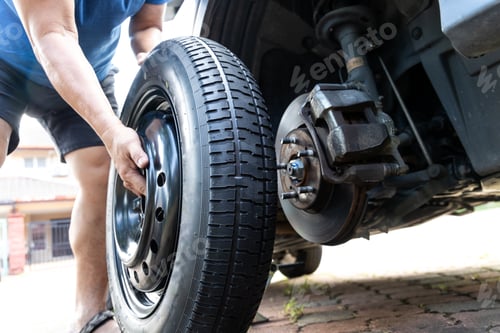 Preview: Person attempting to fix or replace temporary wheel onto vehible after omiting punctured flat tire