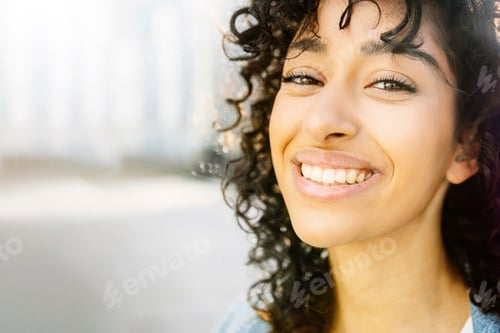 Preview: Closeup portrait of young happy woman smiling at camera outdoors