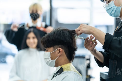 Preview: Asian hairdresser barber team wear mask, cut hair of customer in shop.