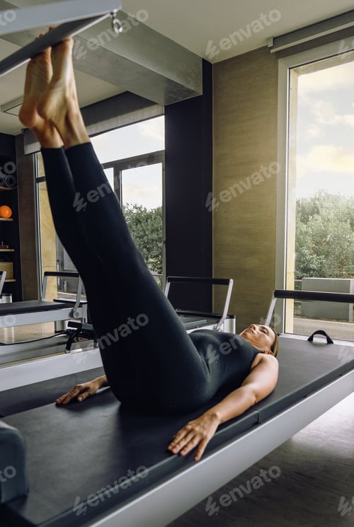 Preview: Woman Doing Pilates Reformer Leg Exercise in Modern Studio