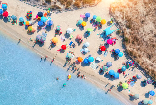Preview: Aerial view of colorful umbrellas on beach, people in blue sea