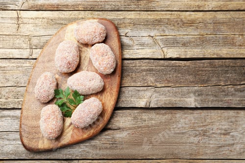 Preview: Uncooked meat patties and parsley on wooden table, top view. Space for text