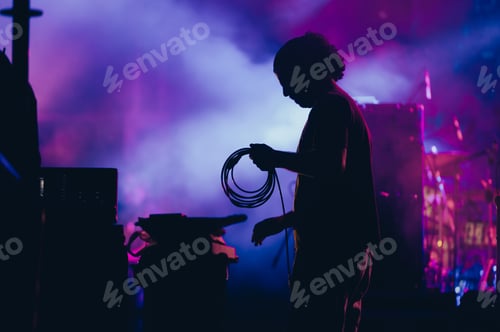 Preview: Silhouette of a stage worker standing on a stage with cables