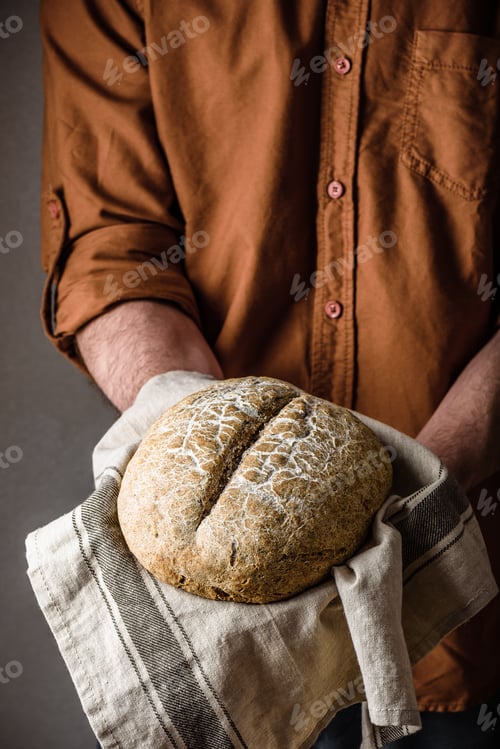 Preview: Man holds a freshly baked rye bread